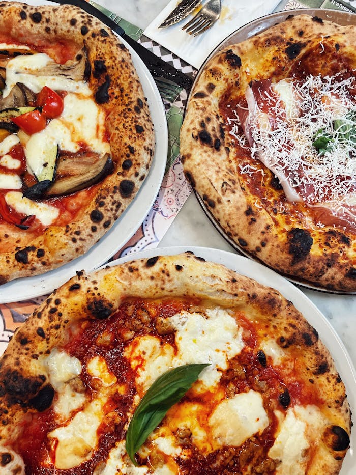 Mastering the First Impression: Your intriguing post title goes here A top view shot of three delicious Neapolitan pizzas with various toppings, perfect for food lovers.